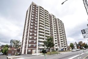 Kitchener apartment for rent - A tall apartment building with a parking lot in front.