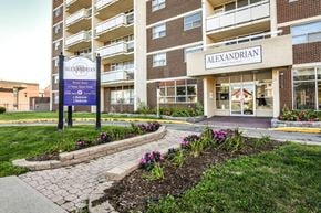 Kitchener apartment for rent - The entrance to the Alexandrian apartment complex is shown with a sign and flower bed in front.