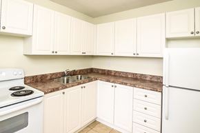 Kitchener apartment for rent - A kitchen with white cabinets and a white refrigerator.