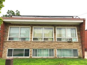 Hamilton apartment for rent - A brick house with a red roof and white curtains on the windows.