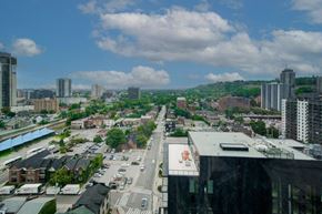 Hamilton apartment for rent - A cityscape with buildings, roads, and cars under a partly cloudy sky.