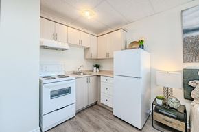 Hamilton apartment for rent - A small, clean, and well-organized kitchen with white appliances and wooden cabinets.