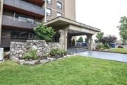 Hamilton apartment for rent - A stone wall and green grass surround a building entrance.