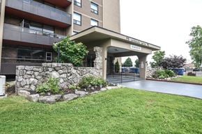 Hamilton apartment for rent - A stone wall and green grass surround a building entrance.