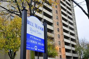 Hamilton apartment for rent - A sign for Bell Manor Rental Suites is displayed in front of a tall building.