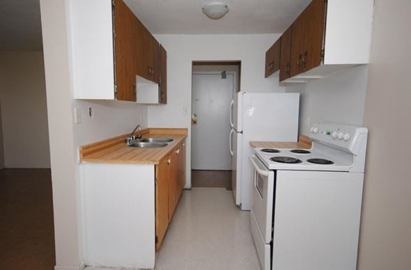 Hamilton apartment for rent - A small kitchen with white appliances and wooden cabinets.
