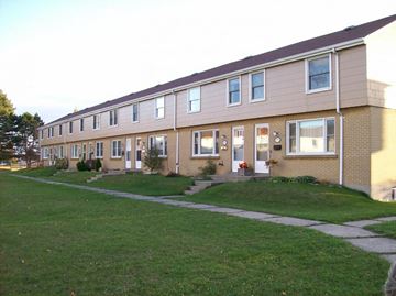 Cobourg apartment for rent - A long building with a green lawn in front.