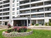 Hamilton apartment for rent - A large white building with a flower bed in front.