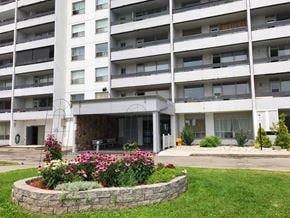 Hamilton apartment for rent - A large white building with a flower bed in front.