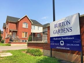 Hamilton apartment for rent - A sign for Burton Gardens 3 Bedroom Townhouses stands in front of a brick house.