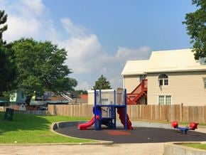 Hamilton apartment for rent - A playground with a blue and red slide in the foreground and a house with a red staircase in the background.