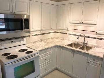 Dundas apartment for rent - A kitchen with white cabinets and a marble countertop.