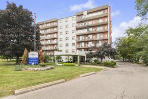 Stoney Creek apartment for rent - A large apartment building with a flag on top and a sign in front.