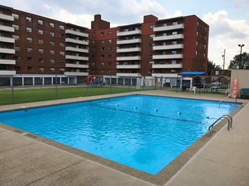 Hamilton apartment for rent - A large swimming pool in front of a red brick apartment building.