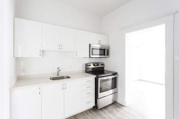 Kitchener apartment for rent - A white kitchen with a sink, microwave, and oven.
