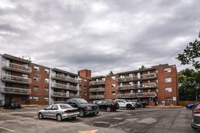 Stoney Creek apartment for rent - A parking lot with cars and apartment buildings in the background.