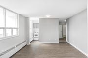 Hamilton apartment for rent - A spacious, empty room with a window on the left and a white appliance in the middle.