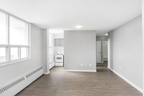 Hamilton apartment for rent - A spacious, empty room with a window on the left and a white appliance in the middle.