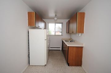 Hamilton apartment for rent - A kitchen with white appliances and wooden cabinets.