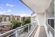 Hamilton apartment for rent - A balcony with a metal railing overlooks a parking lot and apartment buildings.