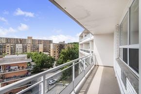 Hamilton apartment for rent - A balcony with a metal railing overlooks a parking lot and apartment buildings.
