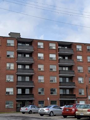 Hamilton apartment for rent - A red brick building with a parking lot in front of it.