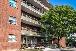 Hamilton apartment for rent - A red brick building with a balcony and a tree in front.