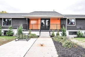 Cambridge apartment for rent - A grey house with an orange door and a black railing.