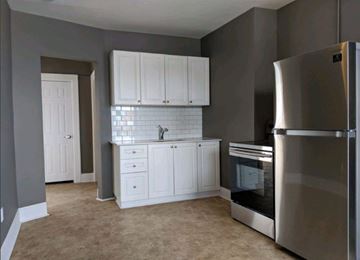 Kitchener apartment for rent - A kitchen with a stainless steel refrigerator and white cabinets.