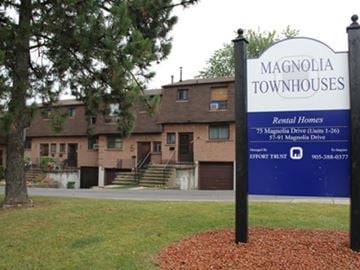 Hamilton apartment for rent - A sign for Magnolia Townhouses stands in front of a building.