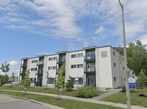 Kitchener apartment for rent - A modern apartment building with balconies and a blue sign in front.