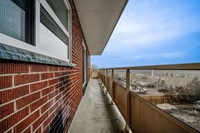 Hamilton apartment for rent - A balcony with a red brick wall and a view of a parking lot.