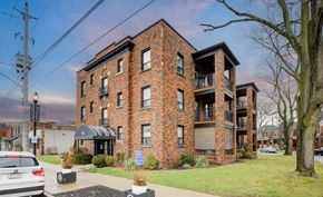 Hamilton apartment for rent - A red brick building with a black awning and a tree in front.