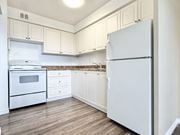 Hamilton apartment for rent - A white refrigerator stands in a kitchen with wooden floors and white cabinets.