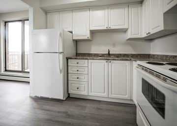Hamilton apartment for rent - A white refrigerator stands in a kitchen with white cabinets and a marble countertop.
