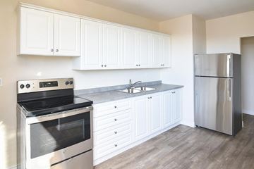 Welland apartment for rent - A kitchen with white cabinets and a stainless steel refrigerator.
