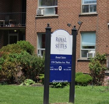 Hamilton apartment for rent - A sign for Royal Suites rental suites stands in front of a brick building.