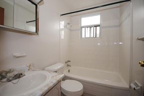 Hamilton apartment for rent - A white bathroom with a tub, toilet, and sink.