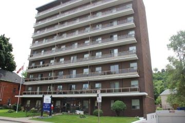 Hamilton apartment for rent - A tall apartment building with a sign in front of it.
