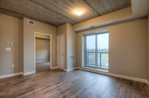 Kitchener apartment for rent - A room with a large window and wooden floors.