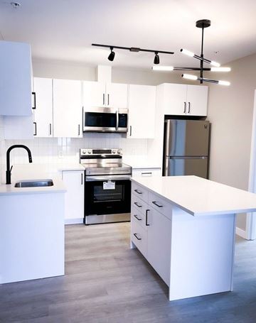 Kitchener apartment for rent - A modern kitchen with white cabinets and a large island.