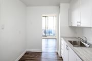 St. Catharines apartment for rent - A kitchen with white cabinets and a wooden floor.