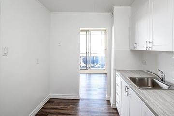 St. Catharines apartment for rent - A kitchen with white cabinets and a wooden floor.