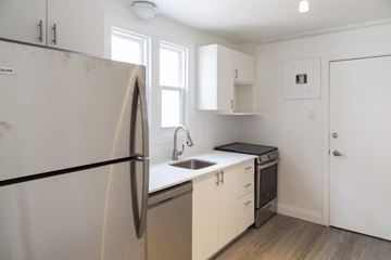 Kitchener apartment for rent - A kitchen with white cabinets and a black fridge.