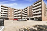 Dundas apartment for rent - A parking lot in front of a multi-story apartment building with cars parked.