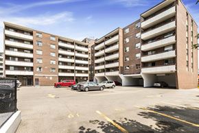 Dundas apartment for rent - A parking lot in front of a multi-story apartment building with cars parked.