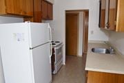 Stoney Creek apartment for rent - A kitchen with a white fridge, wooden cabinets, and a sink.