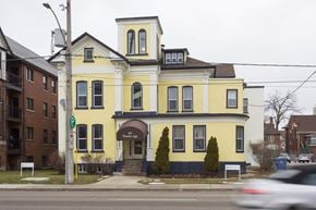 Kitchener apartment for rent - A yellow building with a black roof and a sign that says "The Apk" on it.