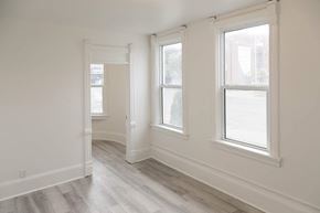 Kitchener apartment for rent - A room with white walls and wood flooring with three windows.