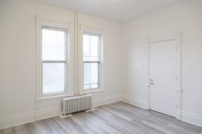 Kitchener apartment for rent - A room with a white door, two windows and a radiator on the floor.
